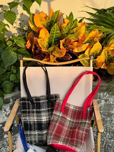 Détail de sacs cabas en laine à carreaux noirs, blancs et rouges sur une chaise