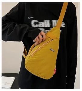 Detail of yellow canvas chest bag with zip pocket and Fei Sheng logo on shoulder strap
