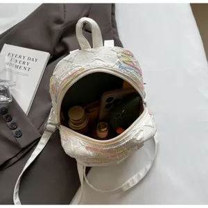 Internal view of a quilted white mini backpack showing space for a phone and cosmetics