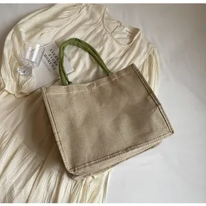 Détail du sac cabas en jute montrant la texture tissée et les poignées vertes