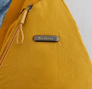 Detailed macro view of yellow nylon fabric texture and metal brand plate on chest bag