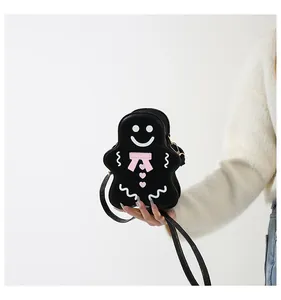 Détail du sac à bandoulière bonhomme de pain d'épices en cuir noir tenu par le mannequin