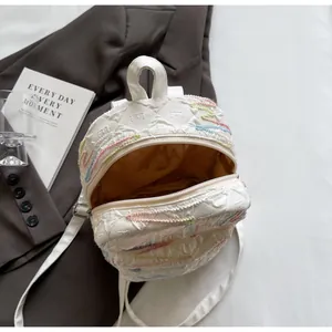 Close-up of white mini backpack featuring colorful wave embroidery and zip closure