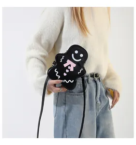 Détail du sac bandoulière noir en forme de bonhomme de pain d'épices porté par un modèle