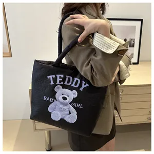 Detail of black puffy canvas tote bag with purple teddy bear print on model side