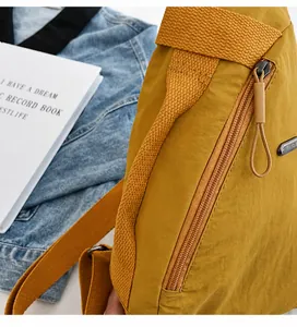 Detail of yellow nylon chest bag showing the reinforced handle and zipper closure