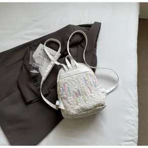 Detail of white mini backpack with colorful quilted embroidery and wave pattern design
