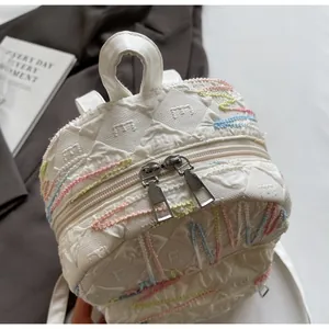 Close-up of cream quilted mini backpack featuring colorful wavy embroidery and dual zippers