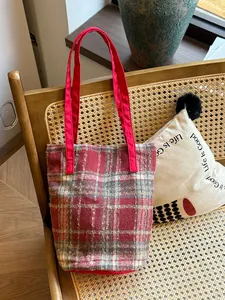 Détail du sac cabas en laine à carreaux rouge et gris avec anses en tissu rouge