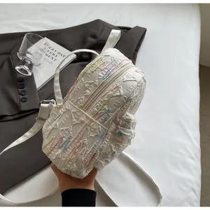Detail of white mini backpack with colorful wave embroidery and texture in lifestyle setting