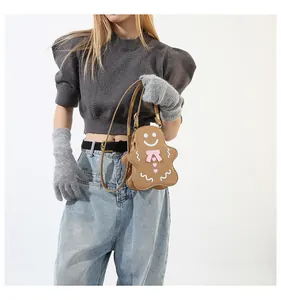 Détail du sac bandoulière bonhomme de pain d'épice avec nœud rose sur tricot gris