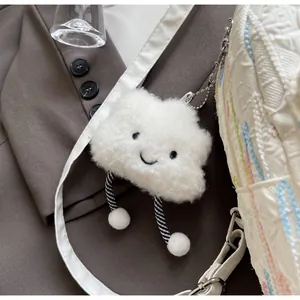 Close-up of a white fluffy cloud keychain with a smiling face on a stylish white bag