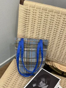 Détail du sac cabas en laine à carreaux bleus avec bandoulière en nylon sur chaise