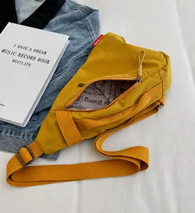 Internal view of a yellow canvas chest bag showing the gray logo lining and zipper detail