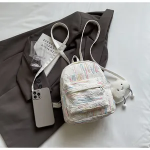 Detailed shot of a white mini backpack with embroidery and a plush cloud charm