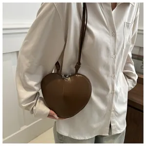 Detailaufnahme der braunen herzförmigen Ledertasche mit Knotenverzierung am Trageriemen