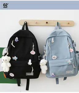 Dettaglio di zaini neri e blu chiaro con badge a cartoni animati e ciondoli a orsetto