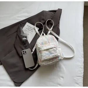 Close-up of white mini backpack with pleated texture and colorful rainbow embroidery