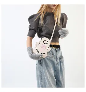 Détail du sac à bandoulière créatif fantôme et pain d'épices avec nœud rose sur tenue grise