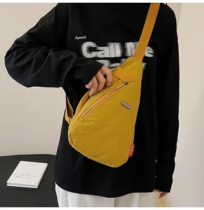 Detail of yellow nylon chest bag featuring adjustable strap and secure zipper pocket