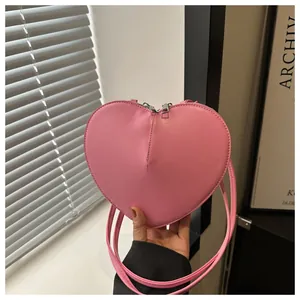 Detail der rosa herzförmigen Umhängetasche mit silbernen Doppelreißverschlüssen und Lederband