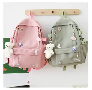 Dettaglio di zaini in nylon rosa e verde con spille carine e ciondolo a orsetto