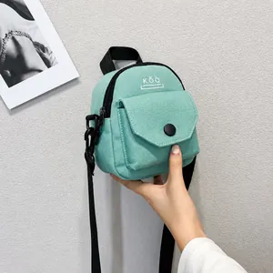 Detail of mint green canvas crossbody bag with KŎQ logo and black adjustable straps