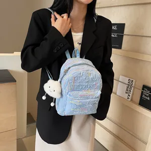 Light blue quilted mini backpack with colorful embroidery and cute cloud charm on a model