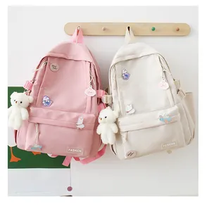 Dettaglio degli zaini rosa e beige con badge carini e ciondoli a forma di orso