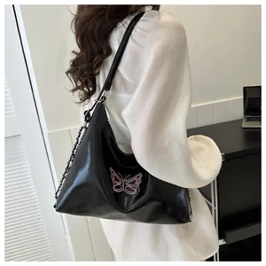 Detail of pink butterfly embroidery on black leather tote with decorative metal chain