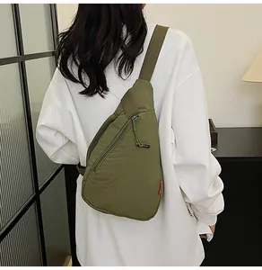 Detail shot of a grass green canvas chest bag with adjustable strap and side zipper