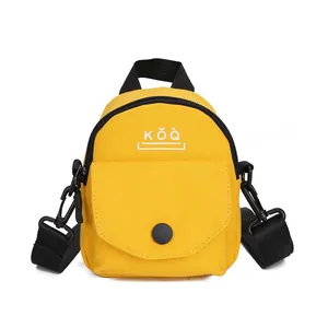 Close-up of a small yellow canvas crossbody bag with black zippers and KOQ logo