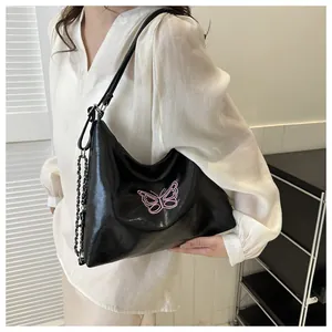 Close-up of black PU leather bag featuring pink butterfly embroidery and metal chain