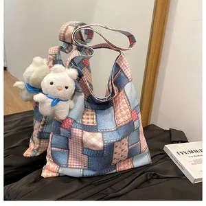 Dettaglio della borsa tote patchwork con denim blu, quadri rosa e ciondolo a coniglio