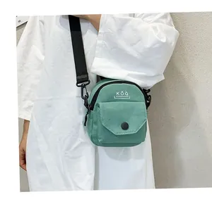 Close-up of mint green canvas crossbody bag with black adjustable strap and snap pocket