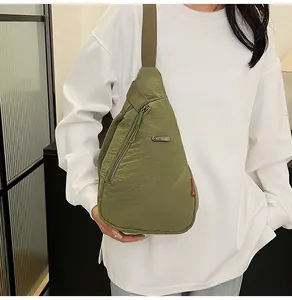 Close-up of military green nylon chest bag with adjustable strap on a white hoodie