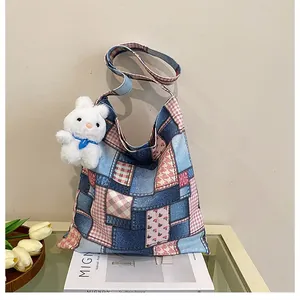 Dettaglio della borsa tote patchwork con denim blu, motivi floreali e ciondolo a coniglietto