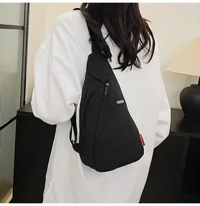 Detail view of the black crossbody chest bag showing adjustable strap and sleek zippers