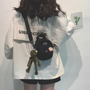 Detail of black canvas mini crossbody bag with logo and cute frog plush pendant