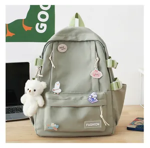 Dettagli dello zaino verde chiaro con distintivi carini e ciondolo orsetto di peluche