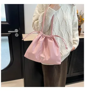 Sac à bandoulière rose à cordon avec nœud métallique argenté sur pull blanc décontracté