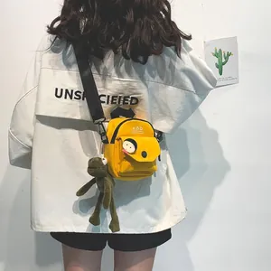 Detail of yellow canvas crossbody bag with mini backpack design and plush frog charm