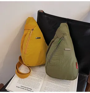 Canvas chest bags in yellow and olive green displayed on a black leather seat over a book