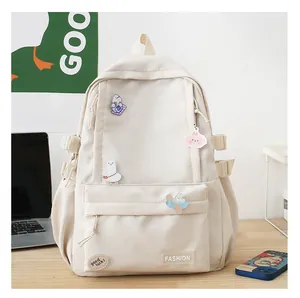 Dettaglio dello zaino in nylon crema con simpatiche spille e fibbie laterali regolabili
