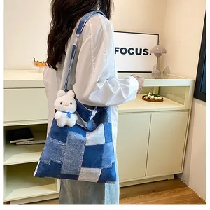 Dettaglio della borsa tote in denim patchwork con ciondolo a coniglio e tracolla