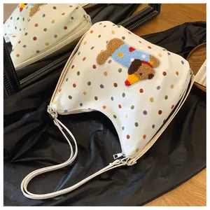 Detailansicht einer weißen Canvas-Tasche mit bunten Punkten und Plüschhund-Stickerei