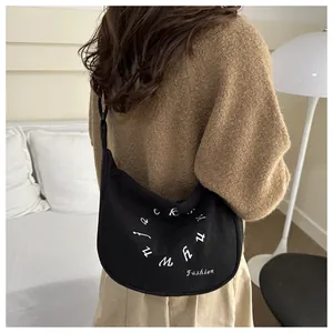 Detalle del bolso hobo negro con bordado blanco llevado por una modelo de costado