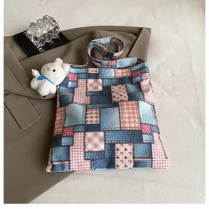 Dettaglio della borsa tote in tela patchwork con motivi blu e ciondolo orso di peluche