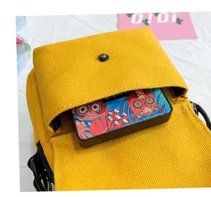 Close-up of yellow canvas crossbody bag featuring a vintage metal buckle and compact interior