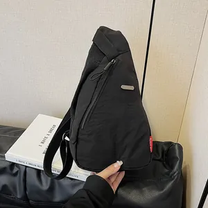 Minimalist black canvas chest bag with adjustable strap shown in a lifestyle interior